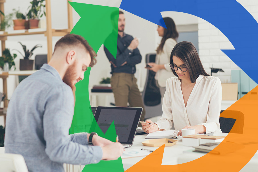 two coworkers sit at their desk using their laptops for thumbnail.