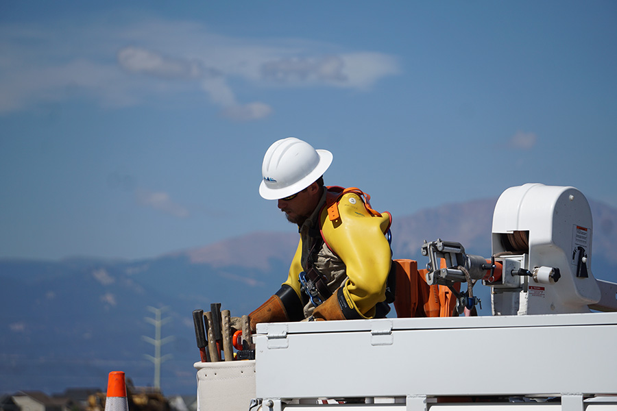 A lineman worker wearing a hardhat looks over the edge of a lift truck.